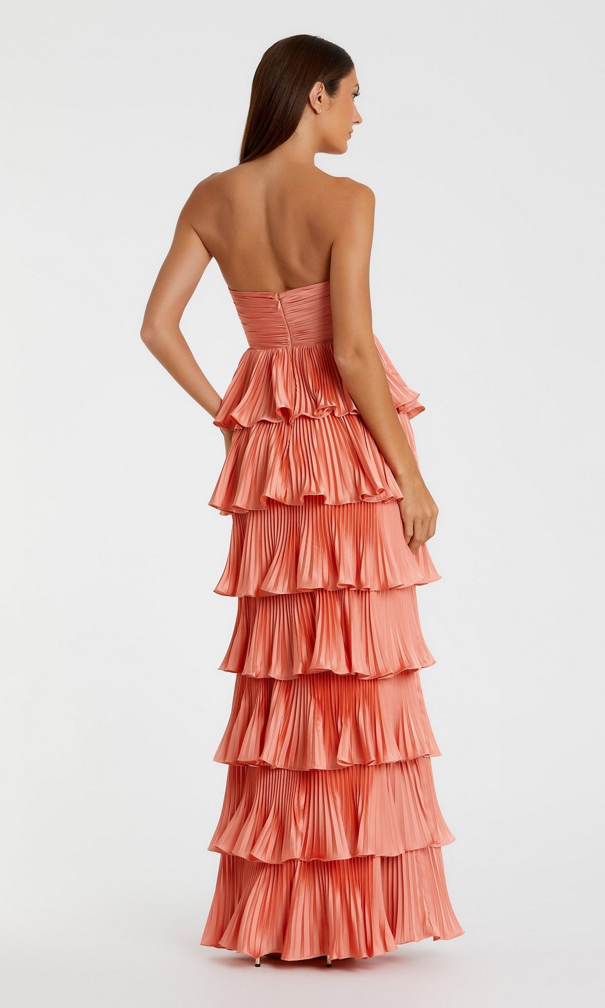 A woman in the Mac Duggal 49981 Long Formal Dress stands facing away, showcasing its strapless, pleated tiered ruffles and elegant floor-length silhouette.